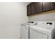 Laundry room features side by side white washer and dryer with dark brown cabinets for storage at 13204 W Via Dona Rd, Peoria, AZ 85383