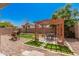 Backyard featuring a pergola with a dining set, set on manicured square grass, and gravel surrounding the space at 15573 W Laurel Ln, Surprise, AZ 85379