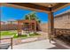 Covered backyard patio with gravel, grass, and a decorative pergola over an outdoor dining set at 15573 W Laurel Ln, Surprise, AZ 85379