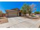 Home showcasing a two-car garage, mature landscaping, and a walkway to the front door at 15573 W Laurel Ln, Surprise, AZ 85379