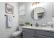 Well-lit bathroom with gray vanity, quartz countertop, and a round mirror at 17538 W Marshall Ln, Surprise, AZ 85388