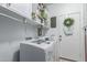 Well-lit laundry room features white shelving, a washer and dryer, and a wreath hanging on the door at 17538 W Marshall Ln, Surprise, AZ 85388