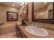Bathroom featuring double sinks with brown cabinets, a walk-in shower, and framed painting at 19700 N 76Th St # 2001, Scottsdale, AZ 85255