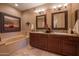 Well-lit bathroom with double sinks, dark wood cabinets, and framed mirrors at 19700 N 76Th St # 2001, Scottsdale, AZ 85255