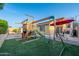 Fun backyard featuring a wooden playset, artificial grass and outdoor dining area with shade at 23932 W Hidalgo Ave, Buckeye, AZ 85326