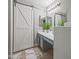Bathroom with double sink vanity, modern lighting, sliding barn door and a decorative rug at 23932 W Hidalgo Ave, Buckeye, AZ 85326