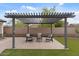 Relaxing backyard seating area under a pergola with a view of manicured landscaping at 31106 N 130Th Ln, Peoria, AZ 85383