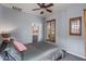 Well-lit bedroom with an attached bathroom, plantation shutters, and ceiling fan at 31106 N 130Th Ln, Peoria, AZ 85383