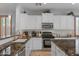 Well-lit kitchen features white cabinetry, stainless appliances, and dark granite countertops at 31106 N 130Th Ln, Peoria, AZ 85383