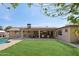 Relaxing backyard featuring an outdoor kitchen, covered patio, and lush green grass at 3830 E Desert Cove Ave, Phoenix, AZ 85028