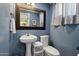 Blue bathroom features a pedestal sink, large mirror, and toilet at 3830 E Desert Cove Ave, Phoenix, AZ 85028
