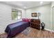 Bright bedroom with brick accent wall, dark wood floors, eclectic decor, and large window overlooking the yard at 3830 E Desert Cove Ave, Phoenix, AZ 85028