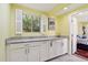 Bright yellow laundry room with white cabinets, granite counters, and view of the bedroom at 3830 E Desert Cove Ave, Phoenix, AZ 85028