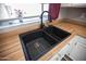 Close-up of a modern kitchen sink with a black faucet, wood countertops, and white cabinetry at 5013 E Shomi St, Phoenix, AZ 85044