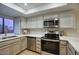 Modern kitchen featuring stainless steel appliances, white cabinets, white countertops, and a view of the backyard at 614 W Kings Ave, Phoenix, AZ 85023
