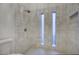 Modern walk-in shower features white tile, dual vertical windows, and a rainfall shower head at 614 W Kings Ave, Phoenix, AZ 85023