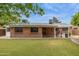 Spacious backyard with a brick house, covered patio with a grill, and a large grassy area at 8629 E Cambridge Ave, Scottsdale, AZ 85257