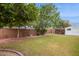 Large backyard with mature trees, a shed, a brick wall, and green grass at 8629 E Cambridge Ave, Scottsdale, AZ 85257