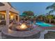 Backyard oasis with a fire pit, lounge chairs, lush greenery, and a sparkling pool at 9443 E Mallory St, Mesa, AZ 85207
