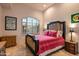 Bright bedroom featuring a rustic wood bed frame, neutral walls, and natural light from the arched window at 9643 E Legacy Ridge Rd, Scottsdale, AZ 85262