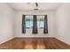 Bright bedroom features hardwood floors, a ceiling fan and curtains framing a window view at 9733 W Purdue Ave, Peoria, AZ 85345