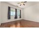 Comfortable bedroom features hardwood floors, a ceiling fan and curtains framing a window view at 9733 W Purdue Ave, Peoria, AZ 85345