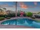 Lush landscaping surrounds an inviting pool with a raised lounging area and an umbrella at 10484 E Mission Ln, Scottsdale, AZ 85258