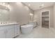 Modern bathroom features a soaking tub, white cabinets, and a walk-in closet access at 1244 N 106Th Pl, Mesa, AZ 85207