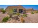 Charming gravel backyard with mature trees and plants, an extended covered patio, and a comfortable porch swing at 14390 W Desert Flower Dr, Goodyear, AZ 85395