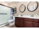 Bathroom with a double sink vanity, framed mirrors, and walk-in shower with a patterned shower curtain at 14390 W Desert Flower Dr, Goodyear, AZ 85395