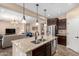 Open-concept kitchen with stainless steel appliances, a granite island, and pendant lights, seamlessly connects to living area at 14390 W Desert Flower Dr, Goodyear, AZ 85395
