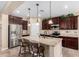 Modern kitchen with dark wood cabinets, stainless steel appliances, a granite island, and pendant lighting at 14390 W Desert Flower Dr, Goodyear, AZ 85395