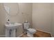 Charming half bathroom featuring a pedestal sink, tile floor, toilet, and a decorative mirror at 14539 W Becker Ln, Surprise, AZ 85379