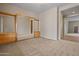Large bedroom with neutral tones, plush carpeting, closet doors with full mirrors, and an open entrance to another room at 14539 W Becker Ln, Surprise, AZ 85379