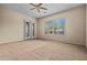Bright bedroom with neutral tones, ceiling fan, and french doors to outside at 14539 W Becker Ln, Surprise, AZ 85379