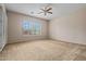 A simple bedroom featuring a ceiling fan, plantation shutters, and carpeted floors at 14539 W Becker Ln, Surprise, AZ 85379