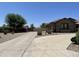 Southwestern-style home with neutral exterior, circular driveway, desert landscaping, and mature trees at 14539 W Becker Ln, Surprise, AZ 85379