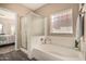 Bright bathroom featuring a shower, tub, and frosted glass block window at 15829 W Boca Raton Rd, Surprise, AZ 85379