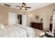 Relaxing bedroom with a ceiling fan, large dresser, soft lighting, and convenient access to closet and bathroom at 15829 W Boca Raton Rd, Surprise, AZ 85379