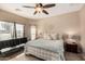 Cozy bedroom features neutral colors, a ceiling fan, a comfortable queen-sized bed, and natural light at 15829 W Boca Raton Rd, Surprise, AZ 85379