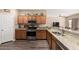 Well-appointed kitchen featuring stainless steel appliances, granite countertops, wood cabinets, and wood flooring at 15829 W Boca Raton Rd, Surprise, AZ 85379