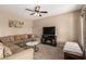 Inviting living room features a cozy sectional sofa, ceiling fan, and entertainment center with built in electric fireplace at 15829 W Boca Raton Rd, Surprise, AZ 85379
