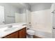 Bright bathroom with a white tiled shower-tub combo and wood-look vanity cabinet topped with white sink and brushed nickel fixtures at 17507 N Costa Brava Ave, Maricopa, AZ 85139