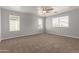 This is a carpeted bedroom with a ceiling fan and two bright windows at 17507 N Costa Brava Ave, Maricopa, AZ 85139