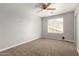 A well-lit bedroom with carpet, a ceiling fan, and a window with blinds for natural light at 17507 N Costa Brava Ave, Maricopa, AZ 85139