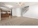 Open-concept living room with carpet flooring, fan, stairs, and adjacent kitchen at 17507 N Costa Brava Ave, Maricopa, AZ 85139