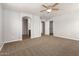 Spacious main bedroom featuring carpet, a ceiling fan, and multiple doorways at 17507 N Costa Brava Ave, Maricopa, AZ 85139