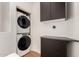 Modern laundry room featuring stacked washer and dryer with sleek cabinetry and gray countertops at 18250 N Cave Creek Rd # 147, Phoenix, AZ 85032