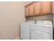 A functional laundry room with modern washer and dryer units and ample cabinet space at 19043 E Seagull Dr, Queen Creek, AZ 85142