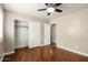 Bedroom with wood floors, ceiling fan, open closet, and view into the hall at 23063 W Loma Linda Blvd, Buckeye, AZ 85326